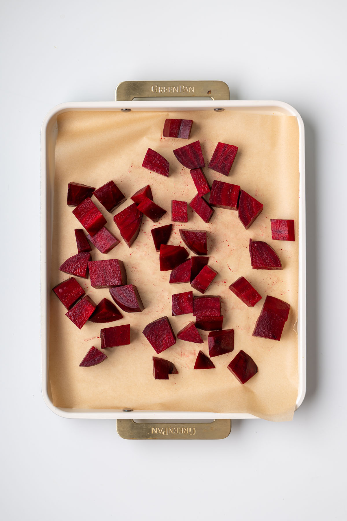 Diced beetroot pieces spread on a parchment-lined baking tray before roasting for a high-protein beetroot medi bowl