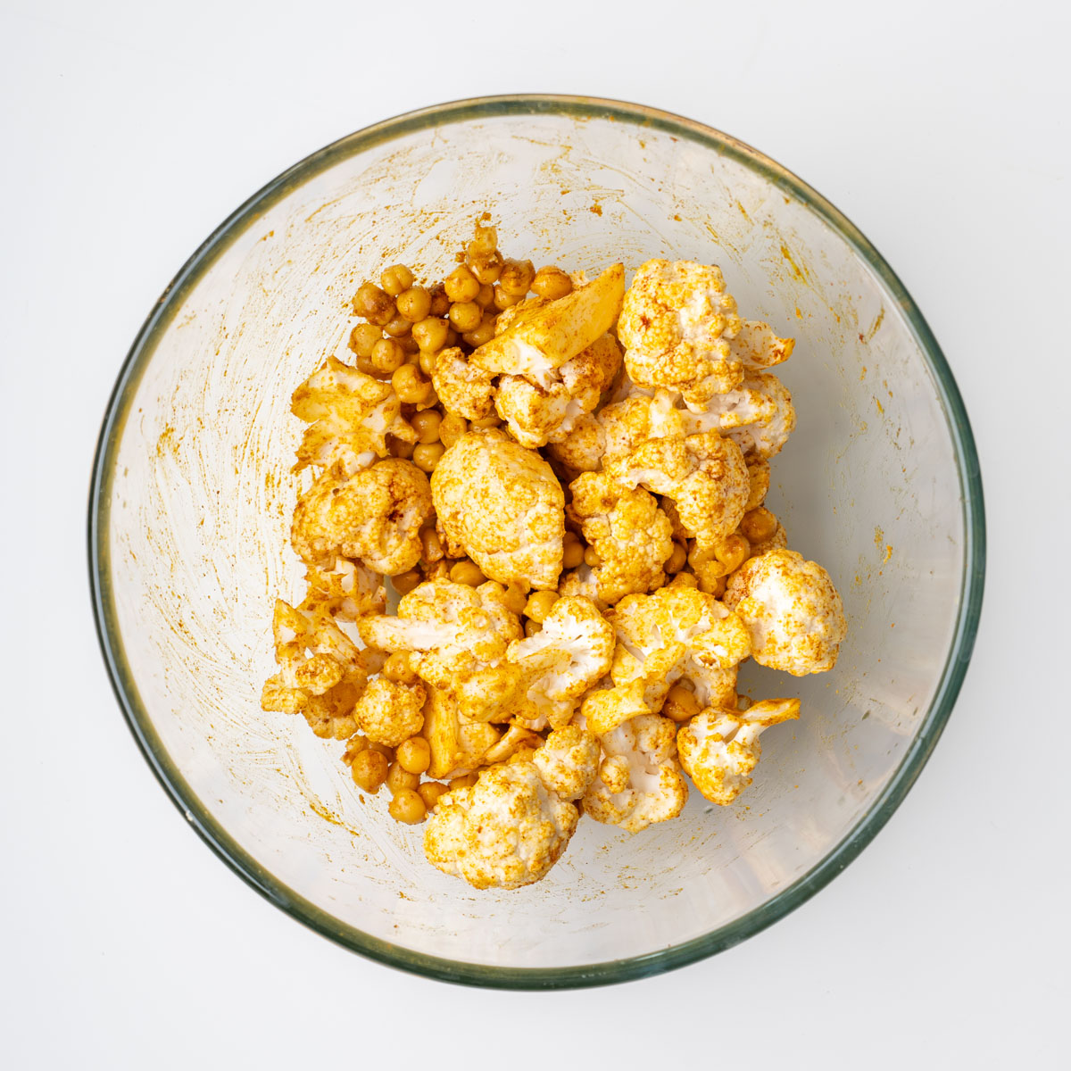 Cauliflower florets tossed with turmeric spice mix in a mixing bowl for a high-protein beetroot medi bowl