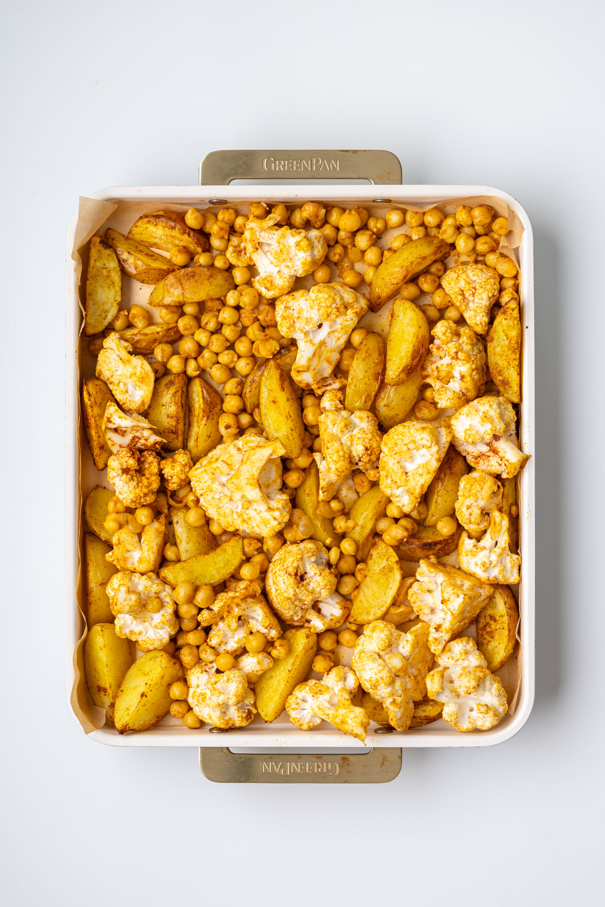 Roasted potatoes, cauliflower florets, and crispy chickpeas with turmeric spice mix on a baking tray