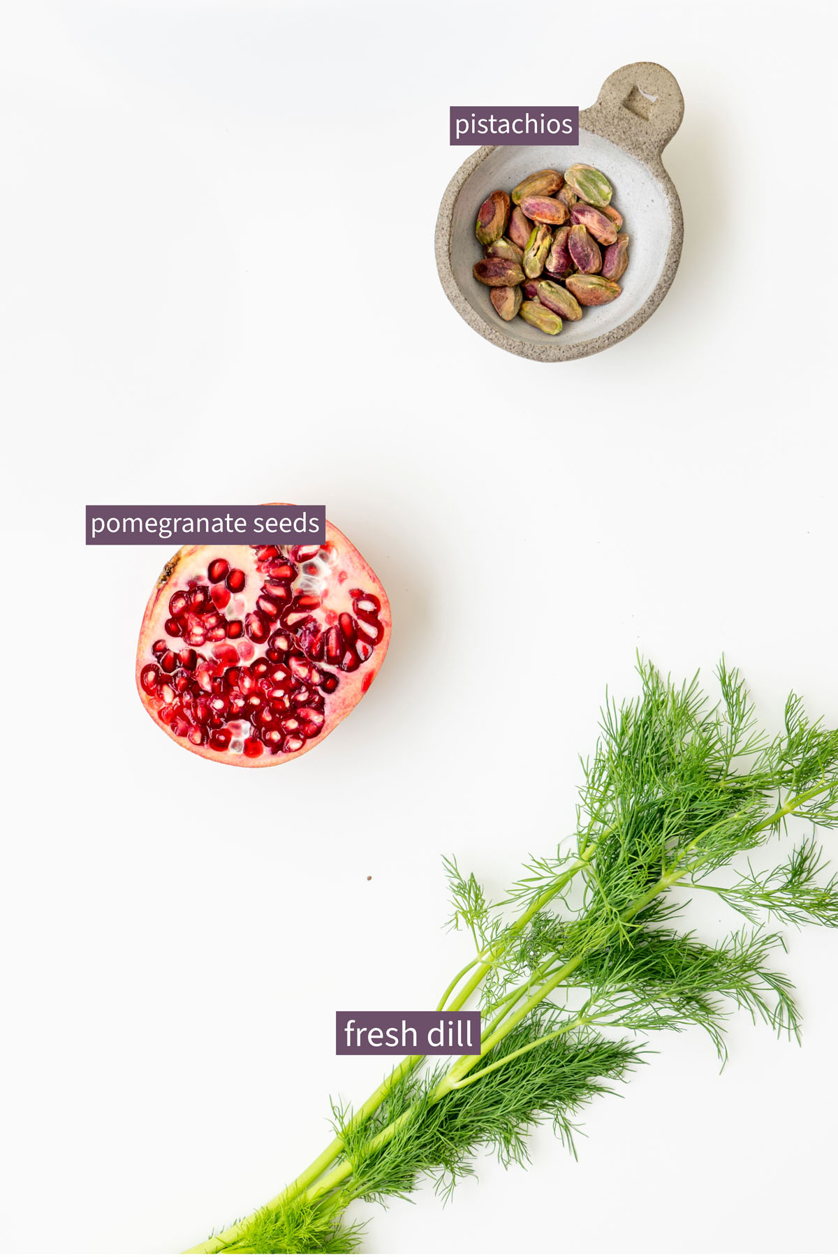 Vibrant topping ingredients for a maple roasted carrots with creamy butter bean dip on a white surface