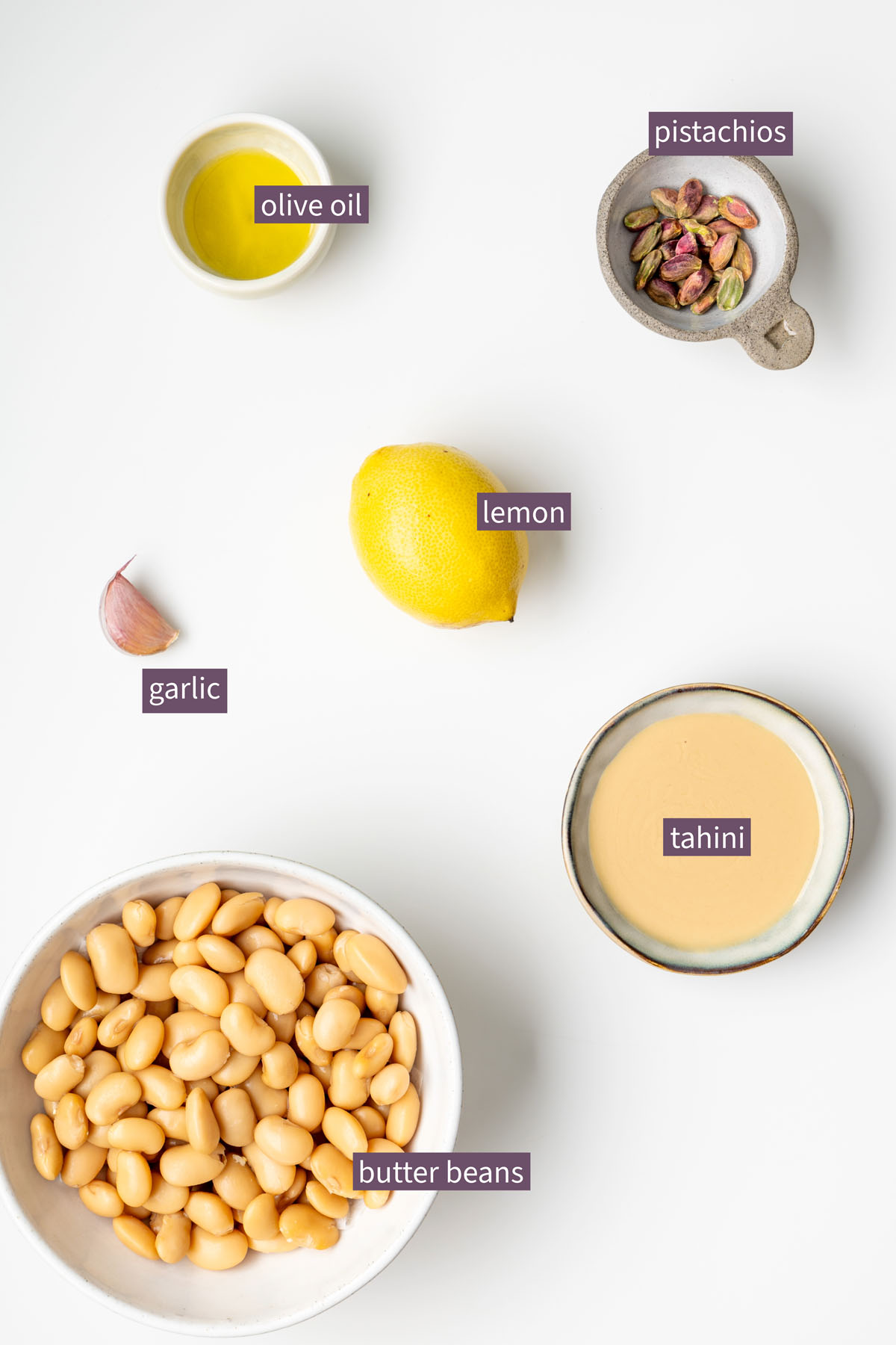 Vibrant ingredients for a creamy butter bean dip on a white surface