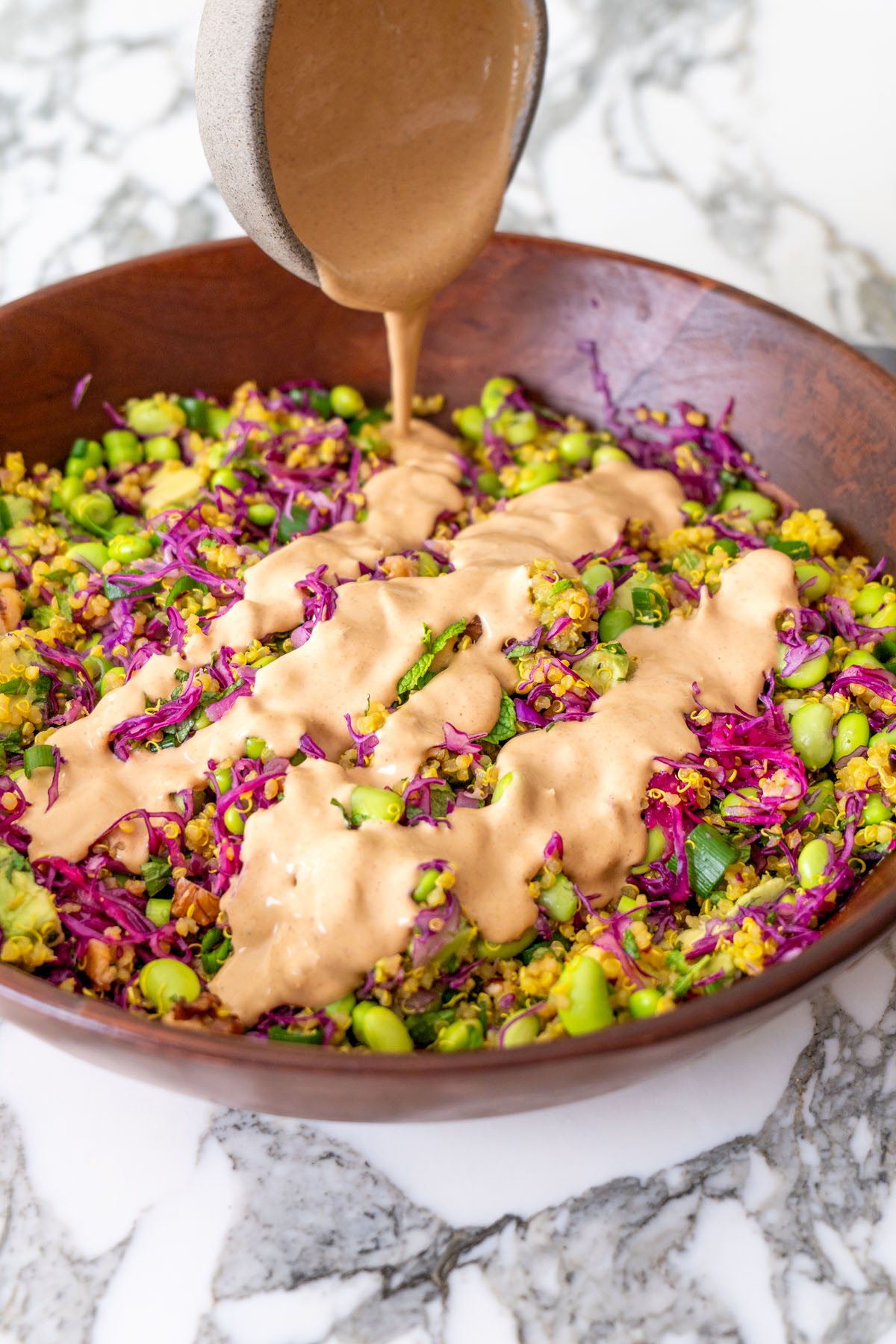 Turmeric quinoa salad drizzled with creamy almond satay dressing and garnished with fresh herbs