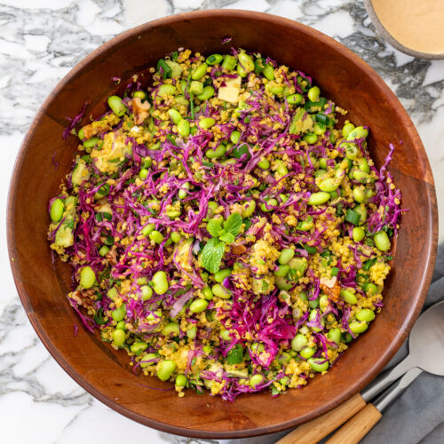 A serving of high-protein turmeric quinoa and edamame salad with red cabbage and almond satay dressing