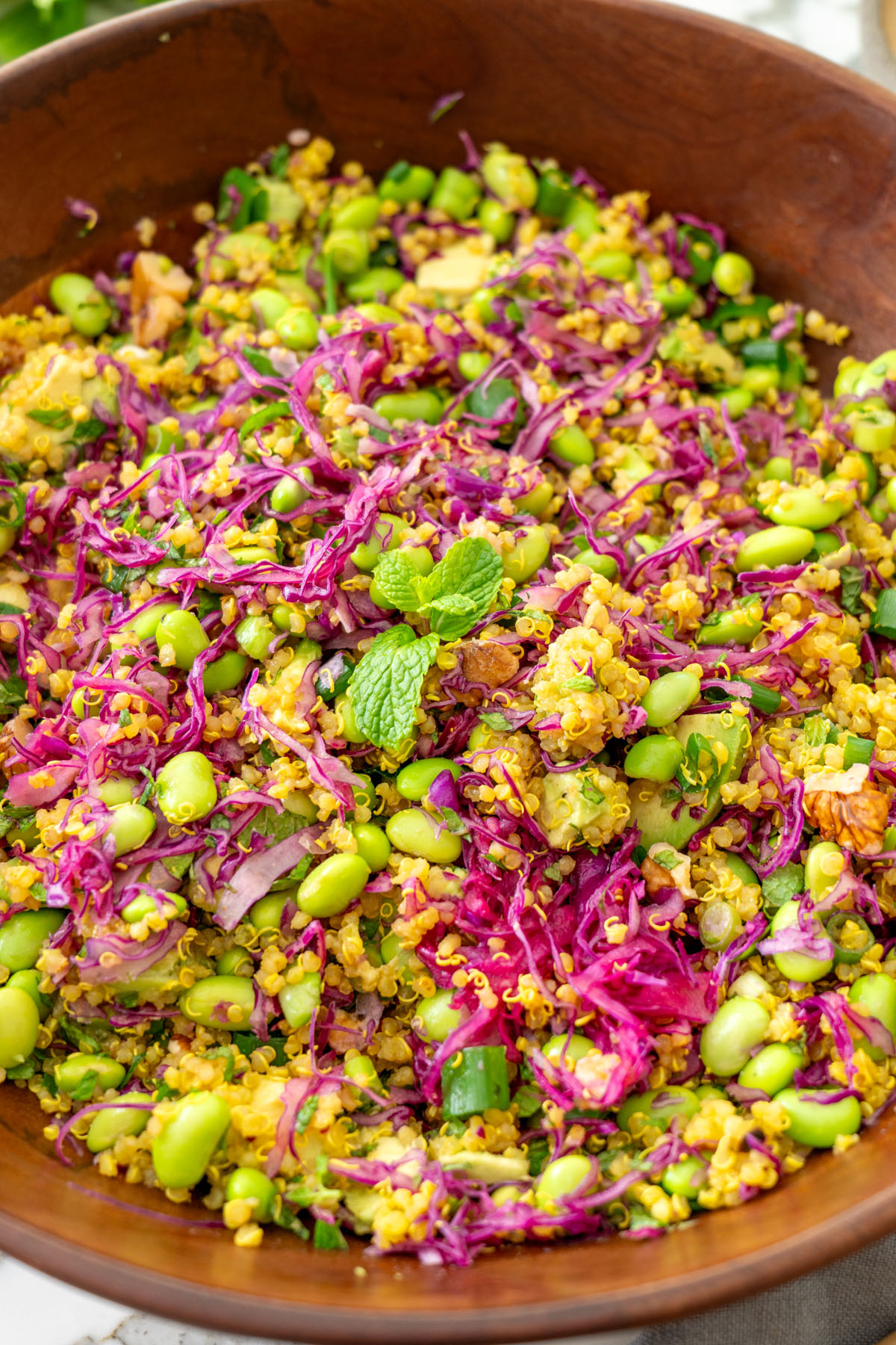 Turmeric quinoa salad with bright edamame, massaged red cabbage, and chopped mint in a bowl