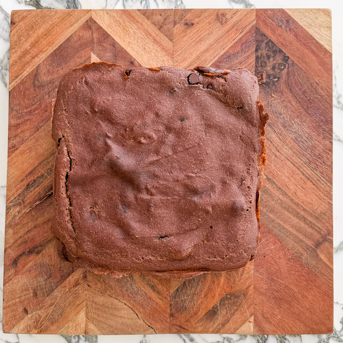 Freshly baked brownie baked oats out of the oven, before icing, on a wooden cutting board.