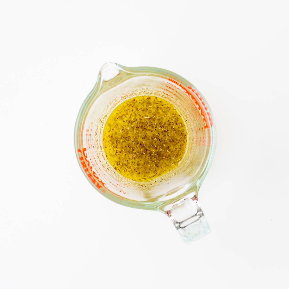 Zesty lime oregano dressing in a glass measuring jug for Cowboy Caviar-inspired salad.