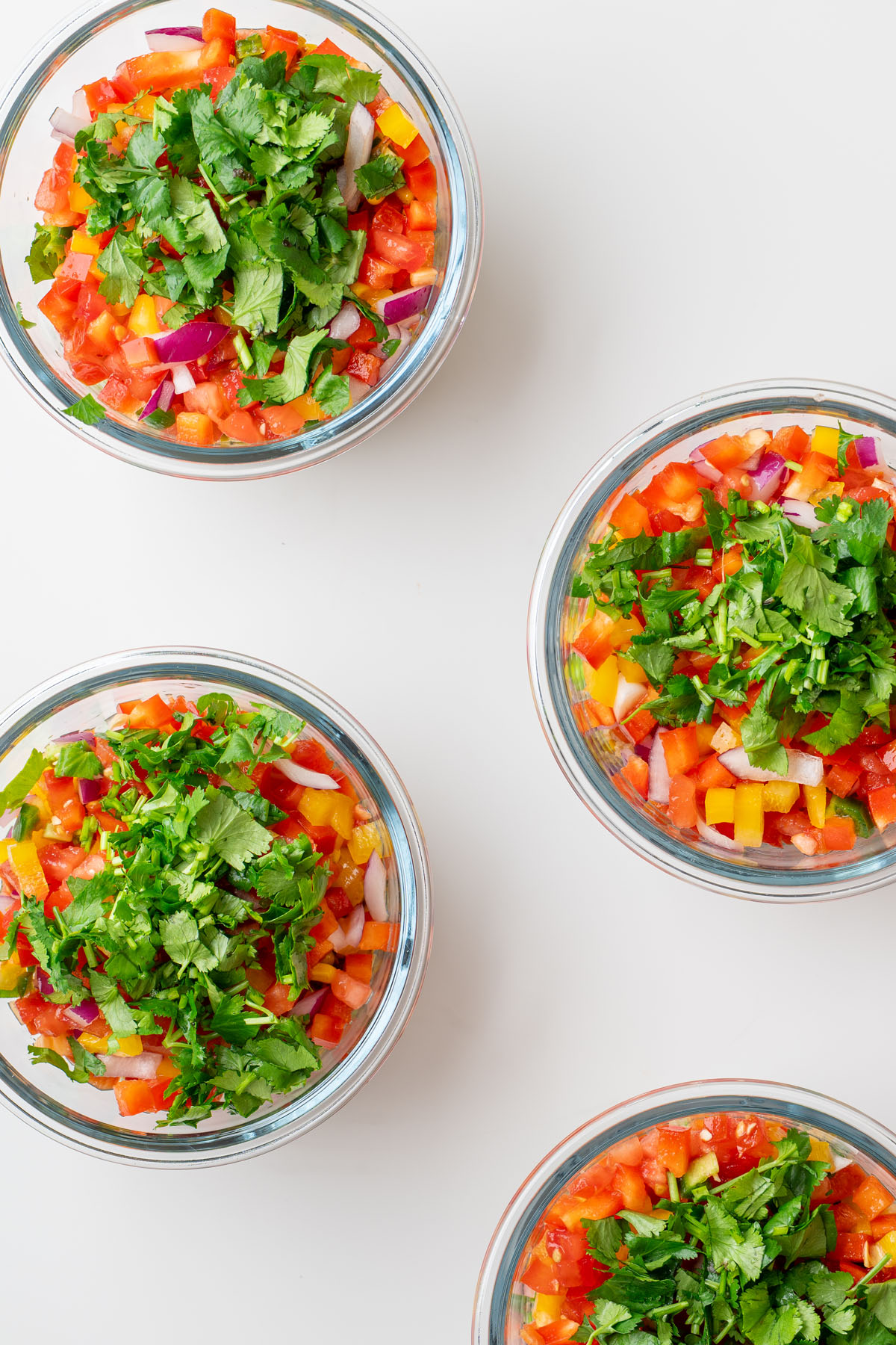 Overhead view of Cowboy Caviar-inspired salad meal prep containers topped with chopped cilantro.