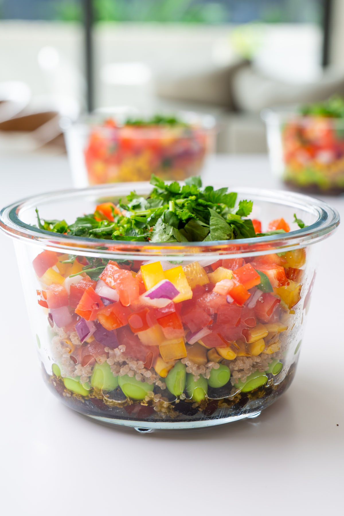 Side view of layered Cowboy Caviar-inspired meal prep salad in glass containers.