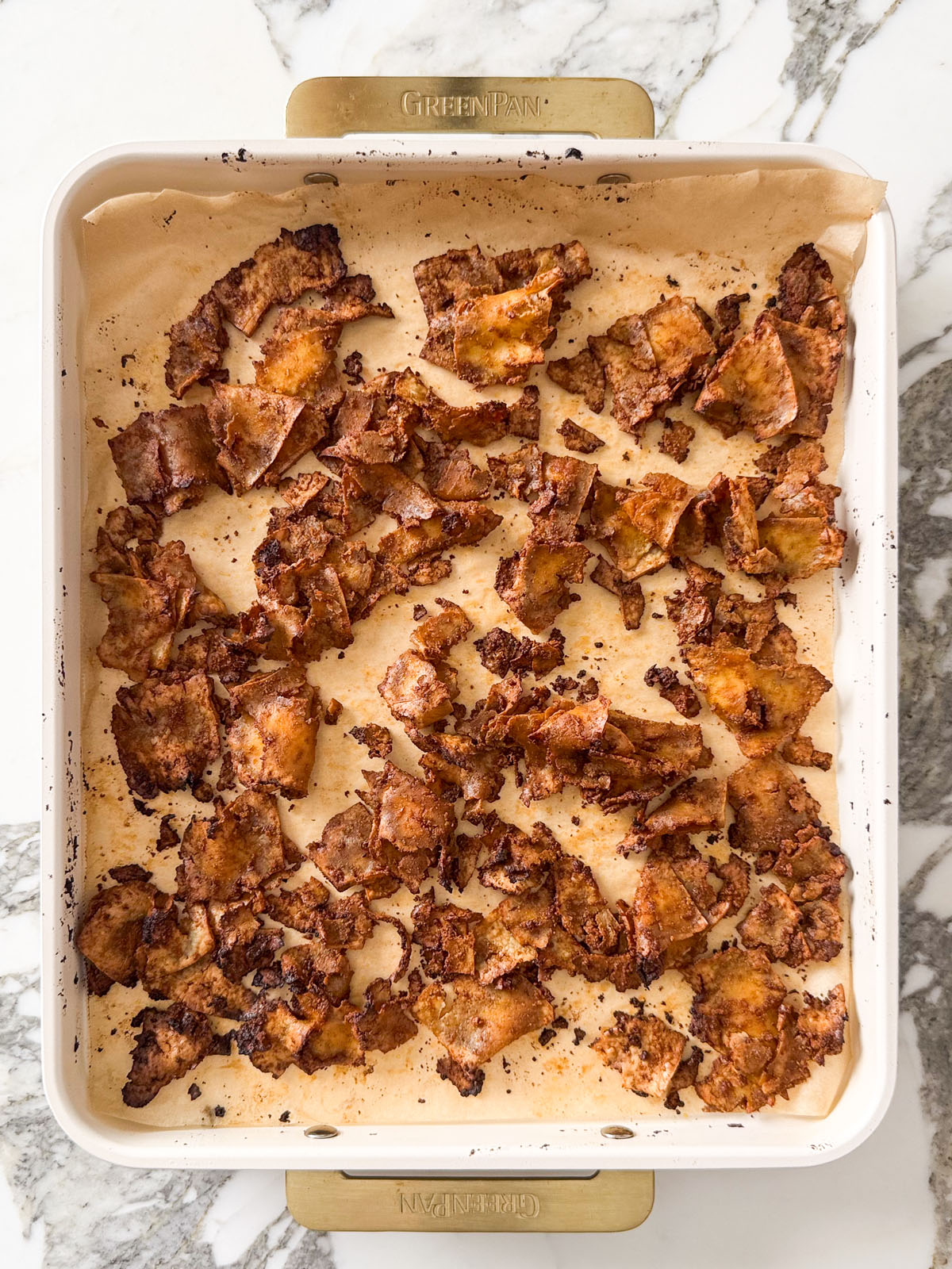Smoky tofu bacon bits on a parchment-lined baking tray after roasting with tamari, maple syrup, and smoked paprika until dark and crisp