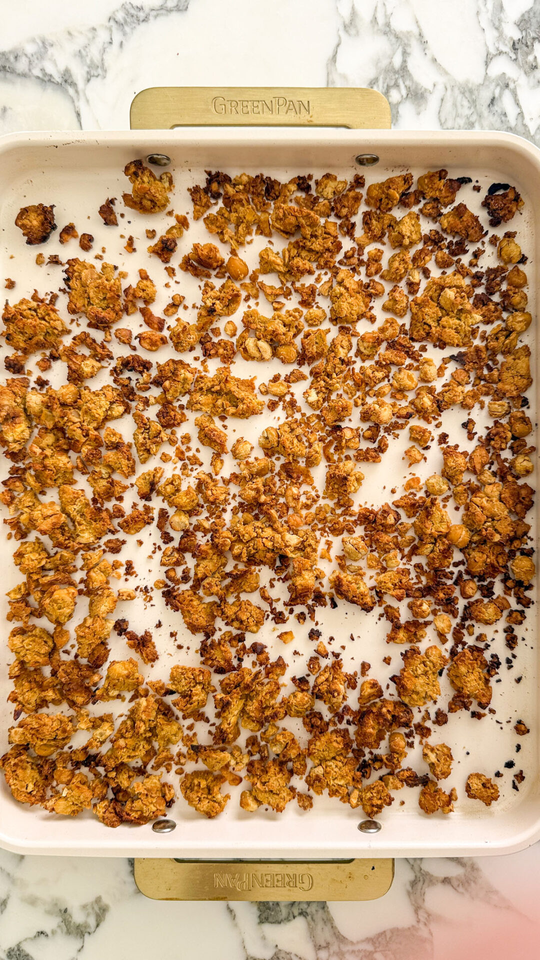 Baked chickpea crumble spread across a cream colored sheet pan, golden and crispy