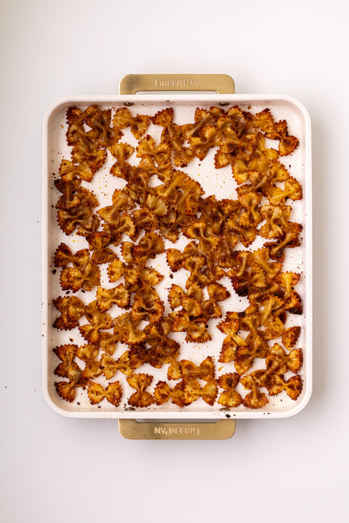 Crispy roasted bowtie pasta arranged in a single layer on a baking tray for viral crispy pasta salad.