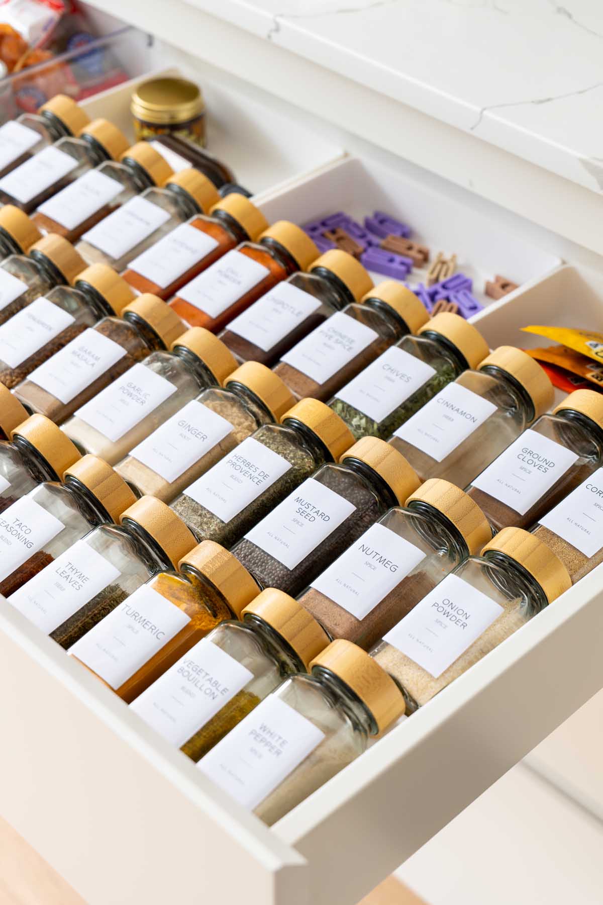 A kitchen drawer fitted with a 3D printed insert that angles rows of labeled spice jars upward so the labels can be read from above