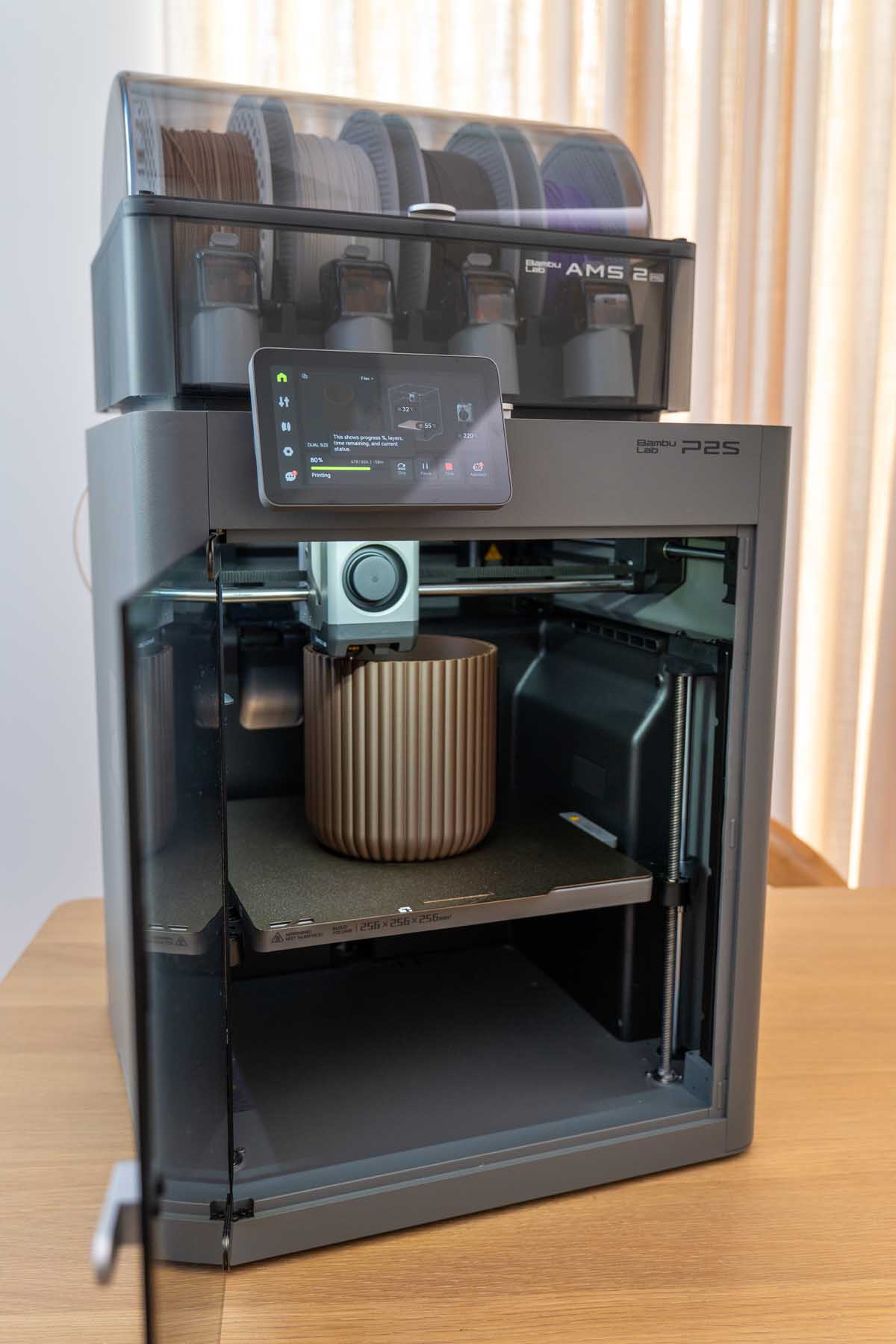 A Bambu Lab 3D printer partway through printing a fluted utensil crock, seen through the front panel