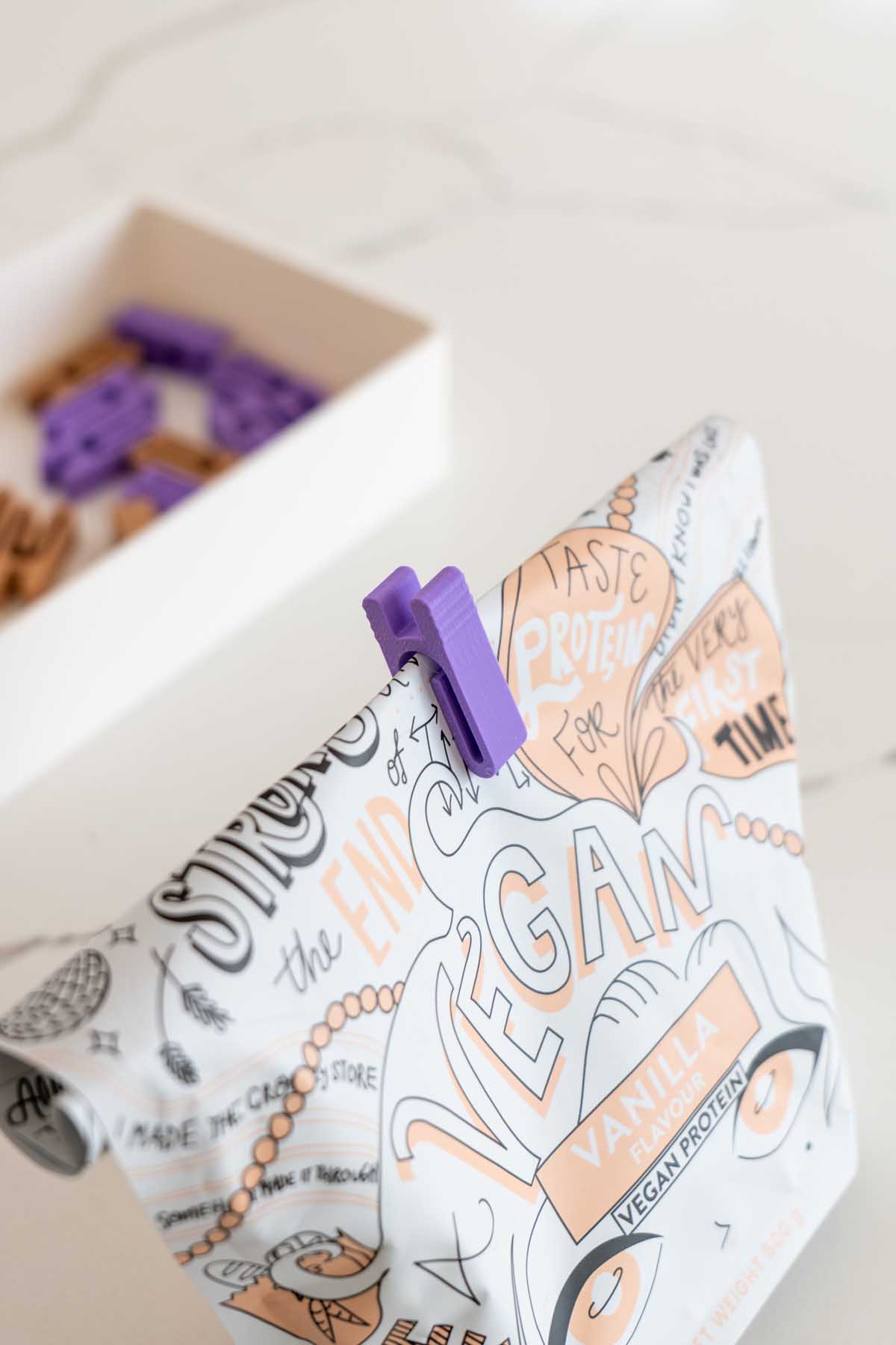 A 3D printed bag clip sealing a food bag closed on a kitchen bench