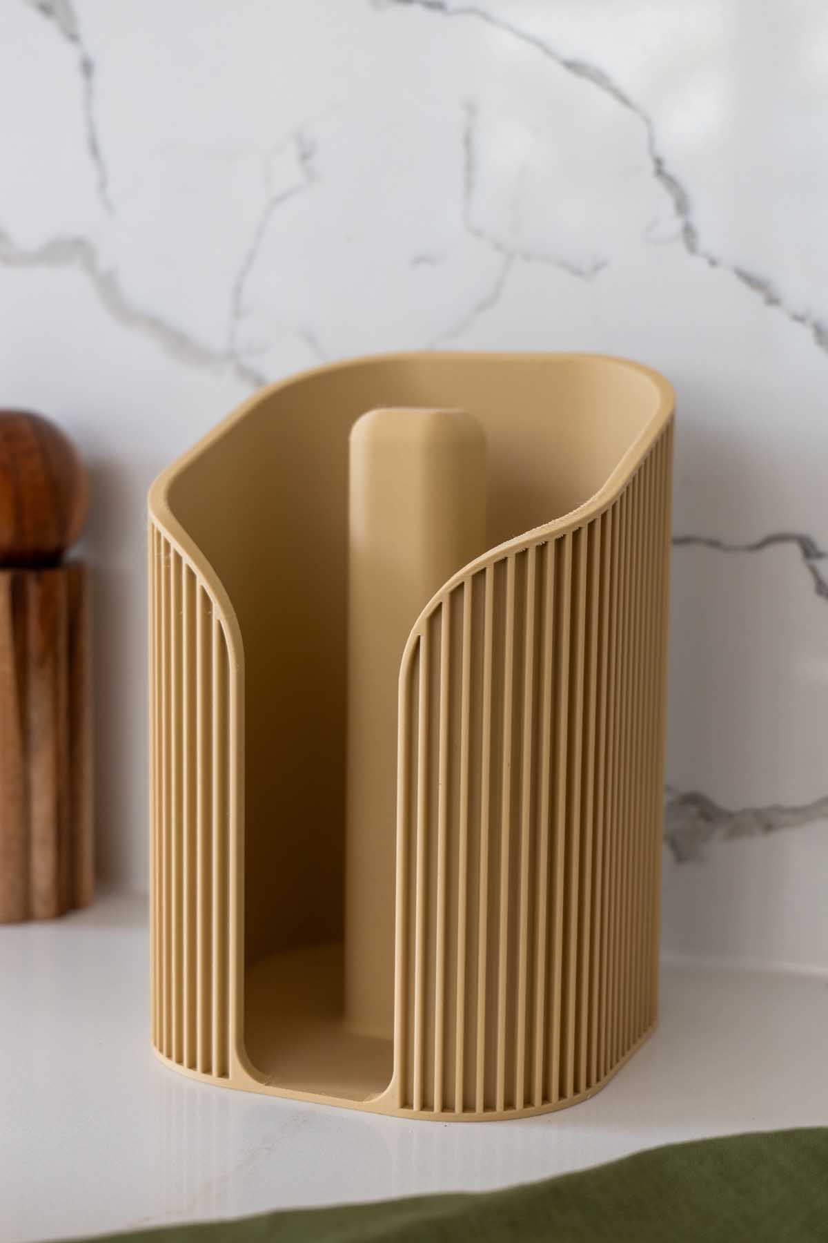 An empty fluted 3D printed paper towel holder on a marble kitchen bench