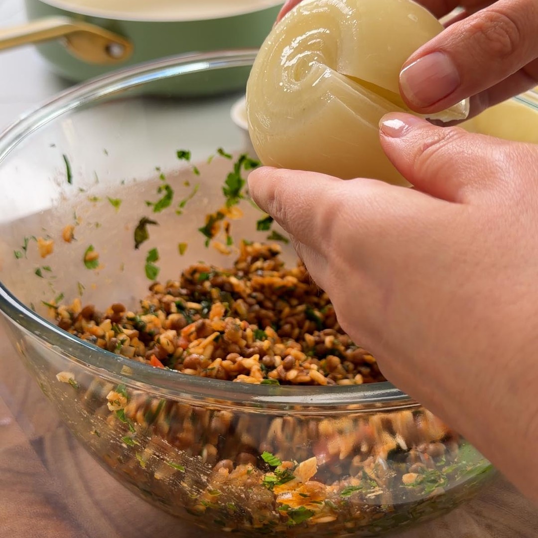 Sarah Cobacho holding a softened onion layer above the bowl of filling.