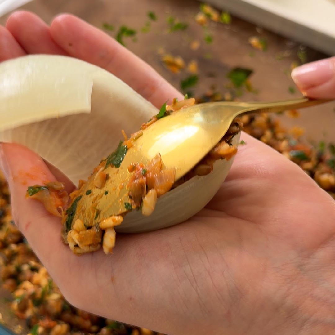 Sarah Cobacho spooning filling into a softened onion layer.