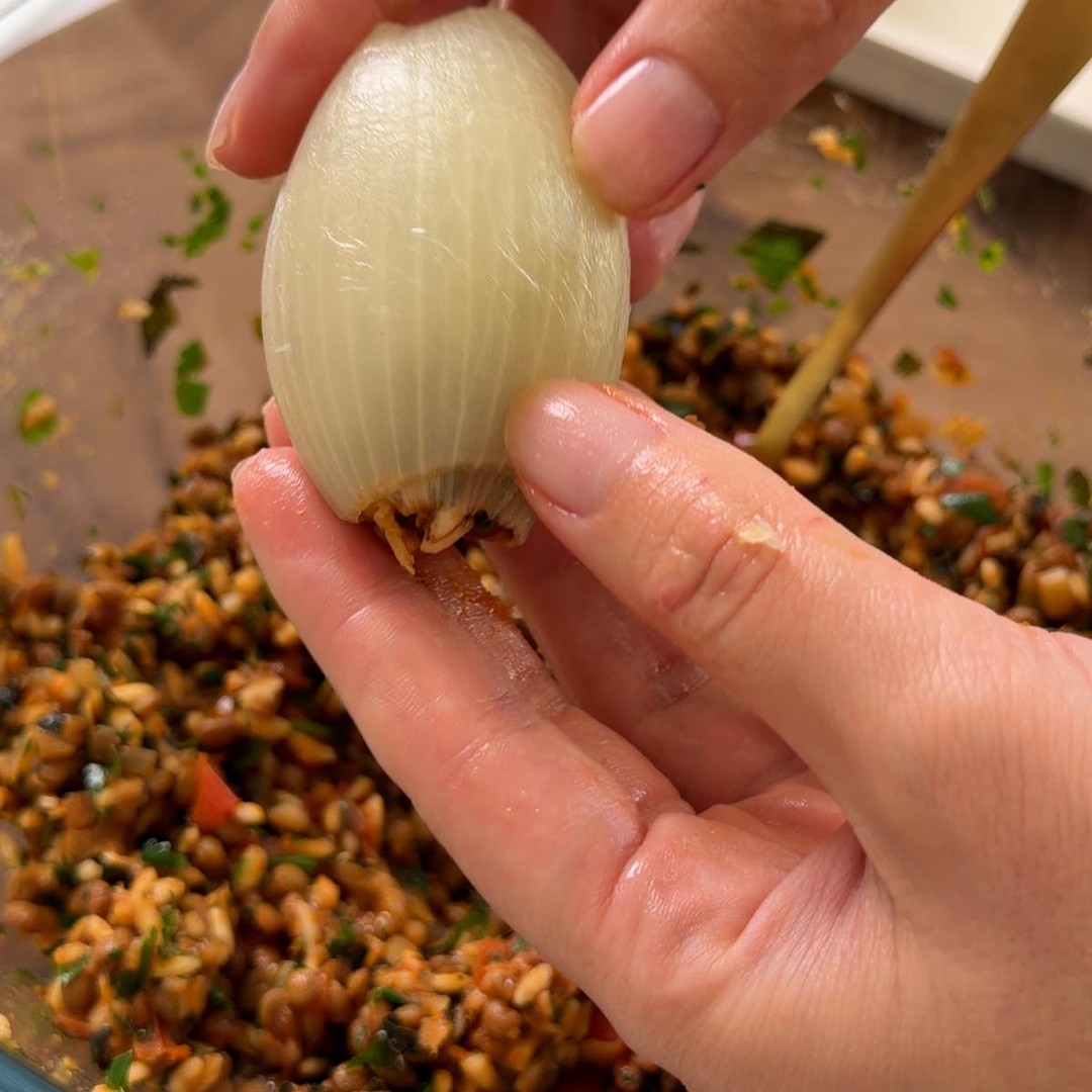 a rolled stuffed onion parcel held in one hand.