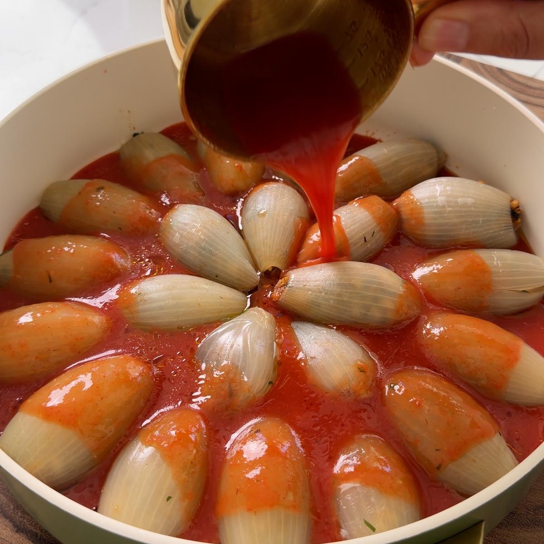 pouring the remaining tomato sauce over the stuffed onions.