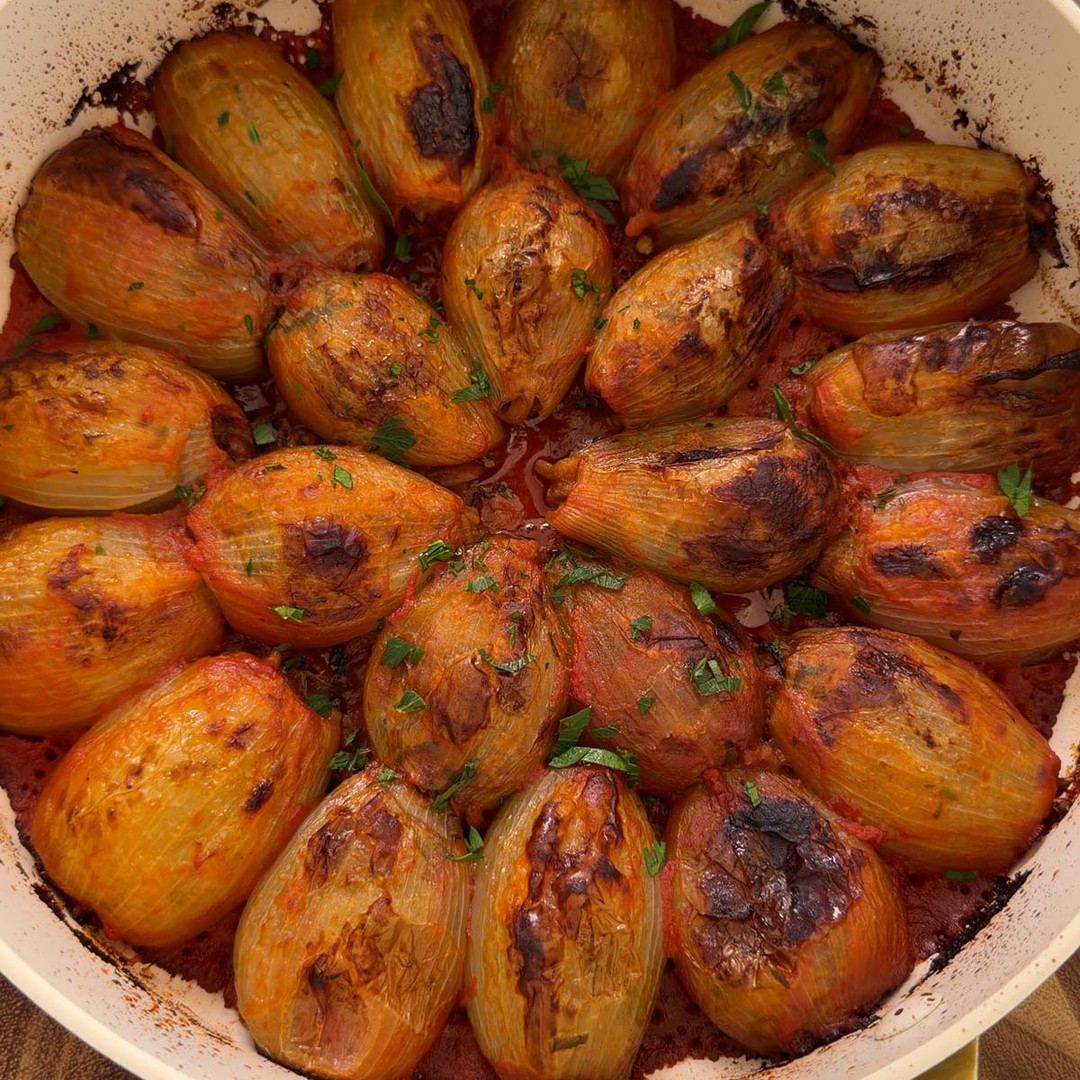 Mediterranean stuffed onions baked until golden in a pan of tomato sauce.