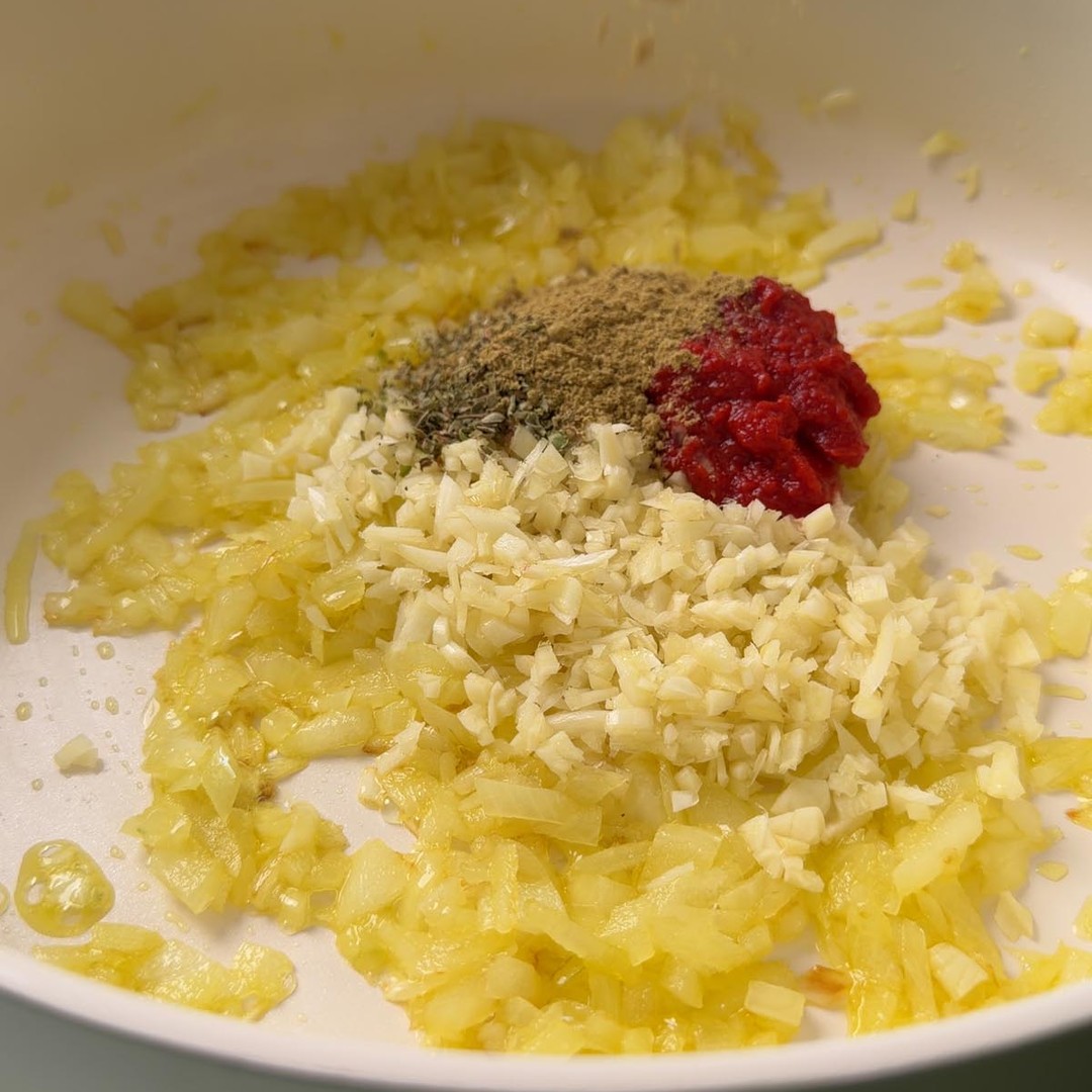 diced onion, minced garlic, tomato paste, cumin and oregano in a pan.