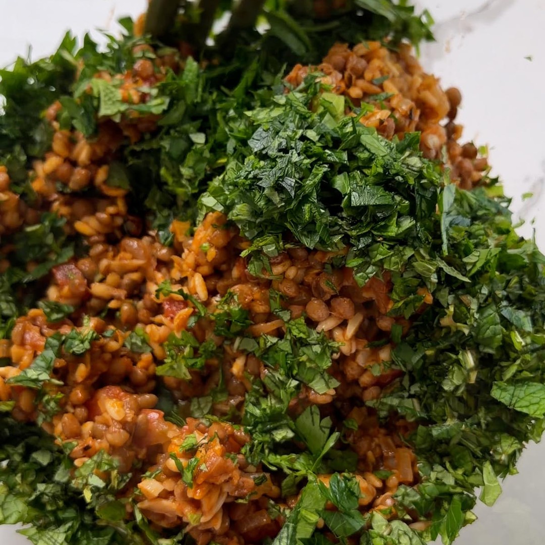 chopped parsley and mint piled on the lentil filling in a glass mixing bowl.