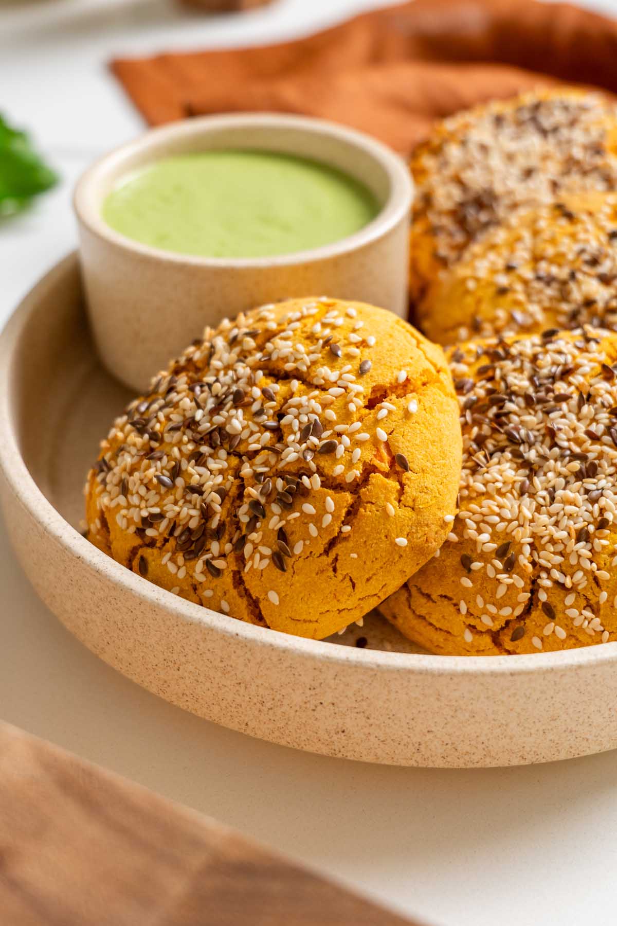 Mexican sweet potato hot pockets in a ceramic bowl, topped with sesame and flaxseeds, with spicy cilantro sauce.
