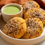 Mexican sweet potato hot pockets on a ceramic plate with a bowl of spicy cilantro sauce.