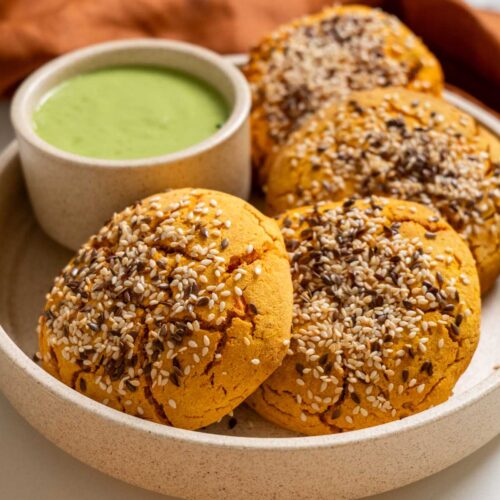 Mexican sweet potato hot pockets on a ceramic plate with a bowl of spicy cilantro sauce.