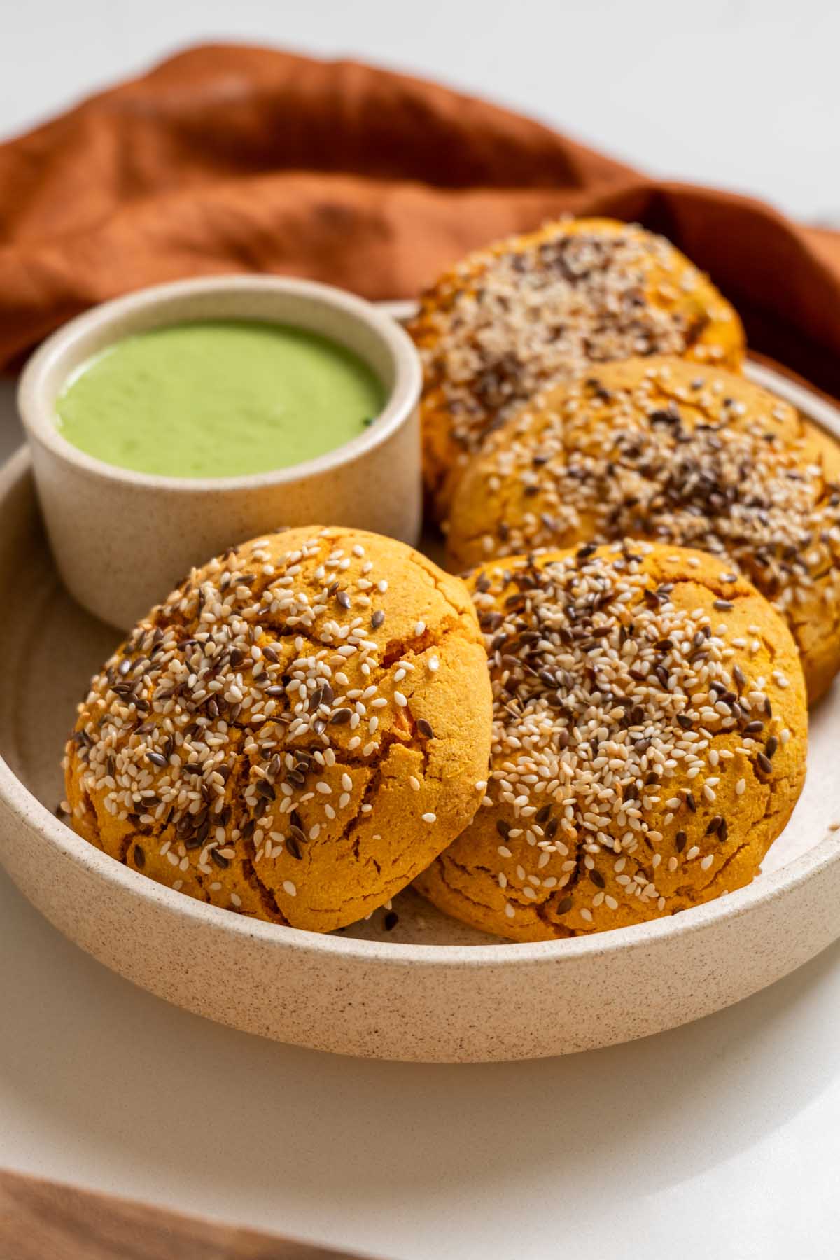 Mexican sweet potato hot pockets on a ceramic plate with a bowl of spicy cilantro sauce.