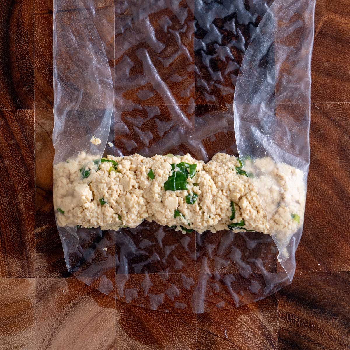 Softened rice paper folded up and over the tofu filling with the sides tucked in, ready to be rolled tight