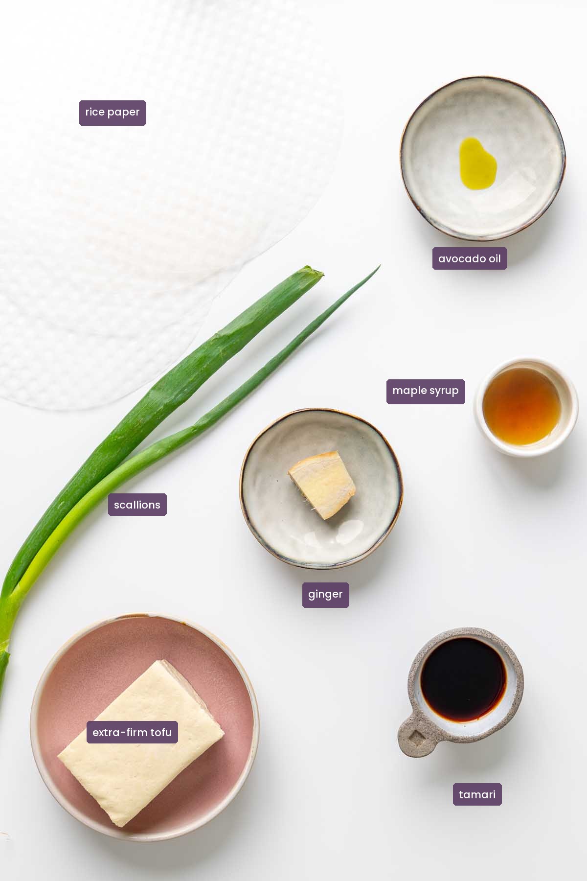 Vibrant ingredients for viral crispy rice paper nuggets on a white surface, including rice paper, extra-firm tofu, scallions, ginger, tamari, maple syrup, and avocado oil