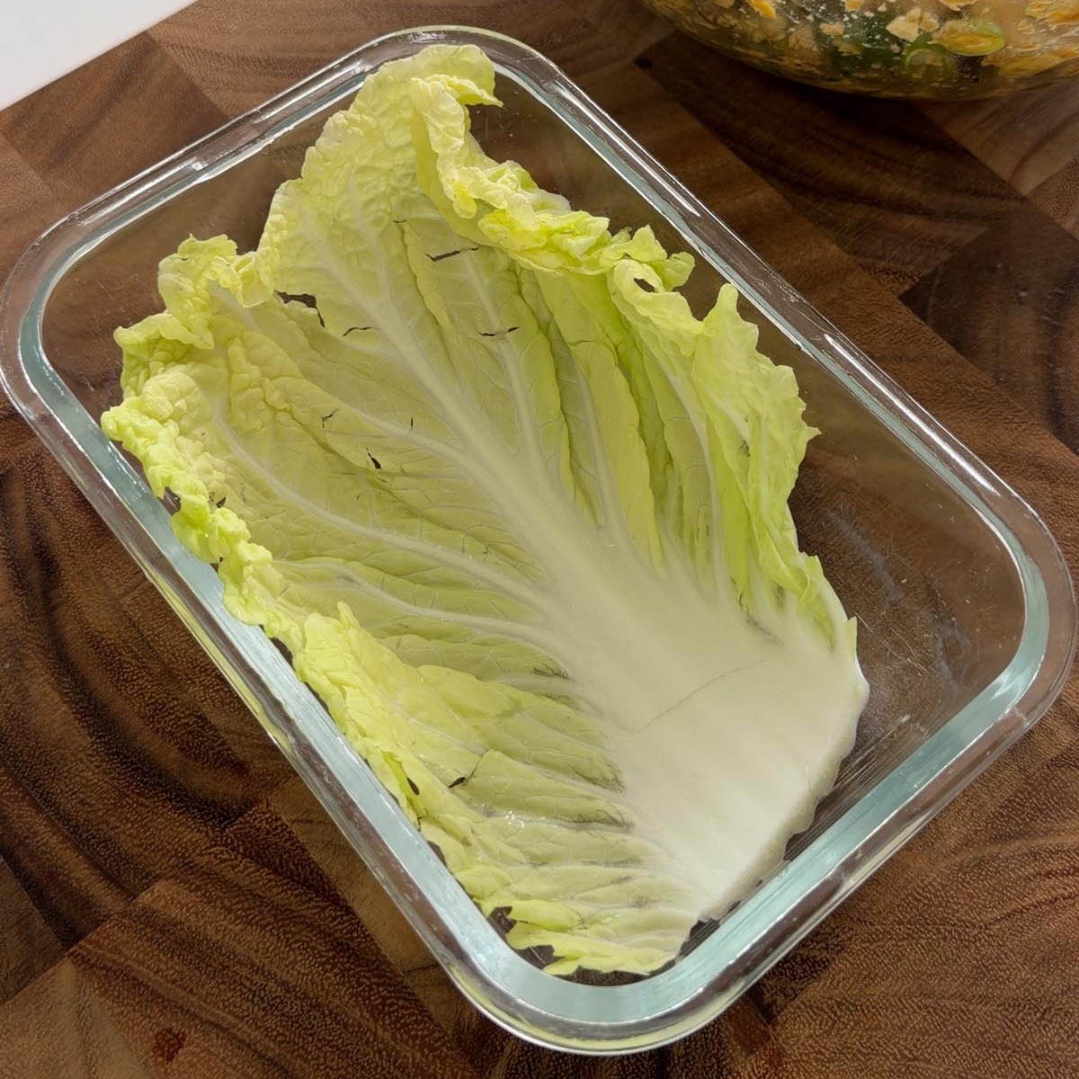 a Chinese cabbage leaf lining the base of a glass dish.