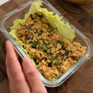 Sarah Cobacho spreading tofu filling over a cabbage leaf in a glass dish.