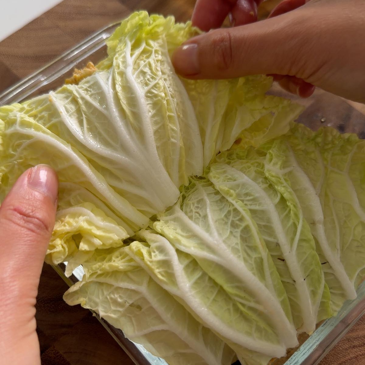 Sarah Cobacho folding the top cabbage leaf over the filling in a glass dish.