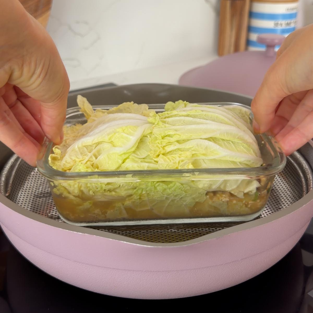 Sarah Cobacho placing the glass dish into a steamer basket over a pan.