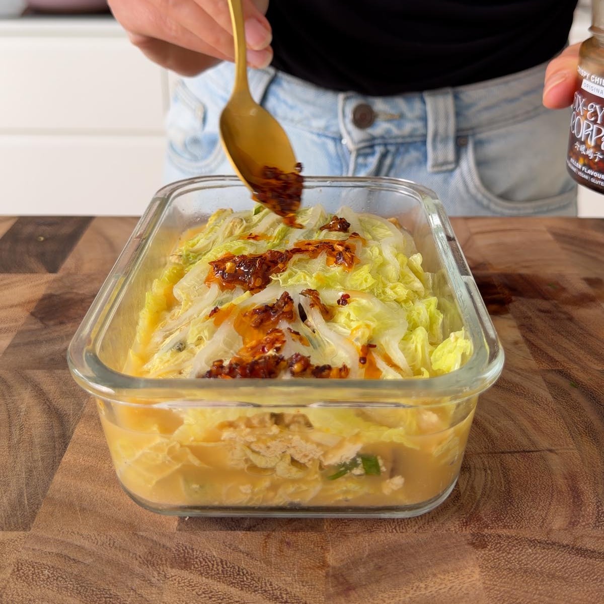 Sarah Cobacho spooning crispy chili oil over the steamed cabbage soup dumpling lasagna.