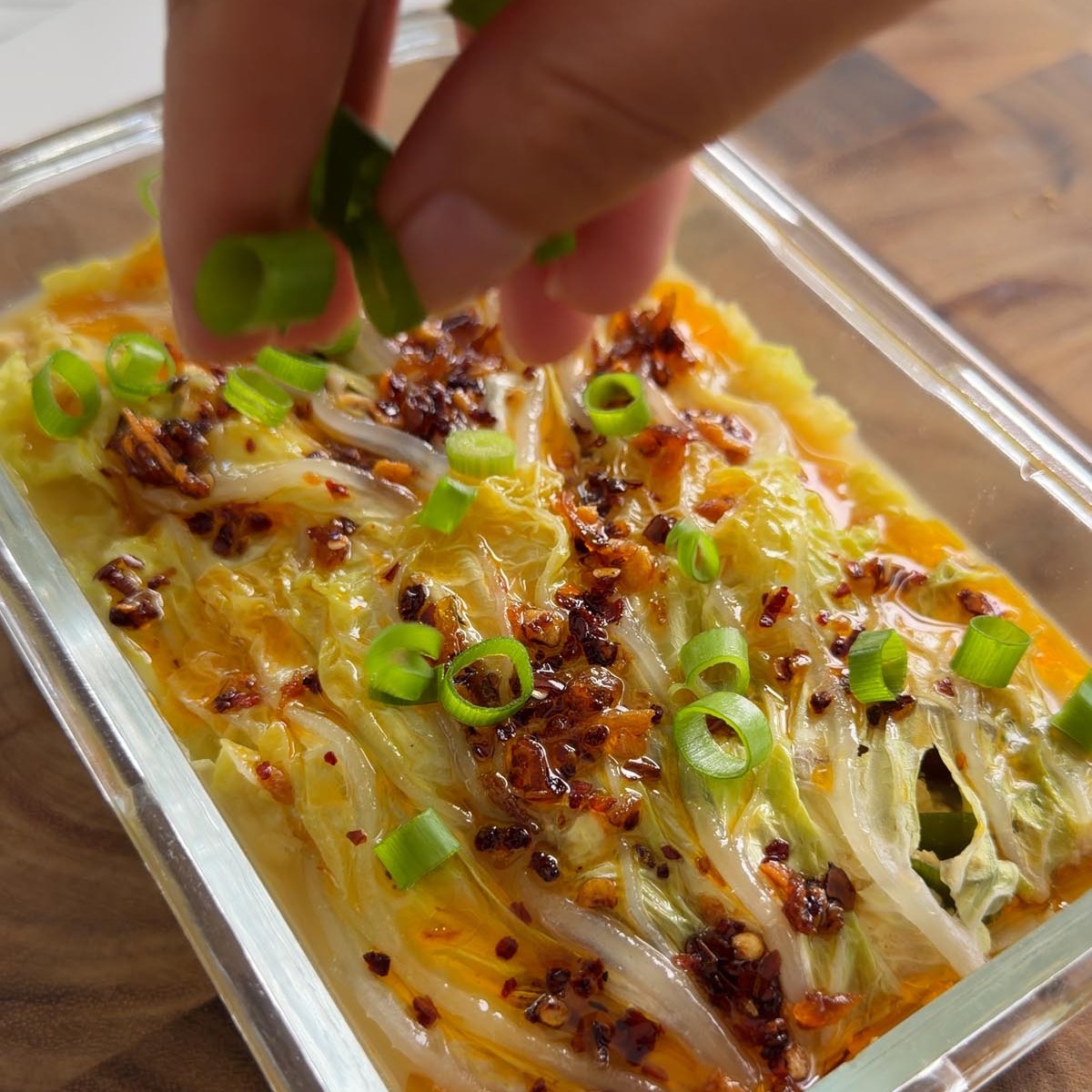 Sarah Cobacho sprinkling scallions over the cabbage soup dumpling lasagna.