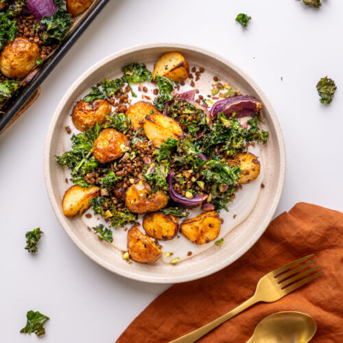 sheet pan potato and crispy kale bowl with tahini yogurt sauce and crushed pistachios.