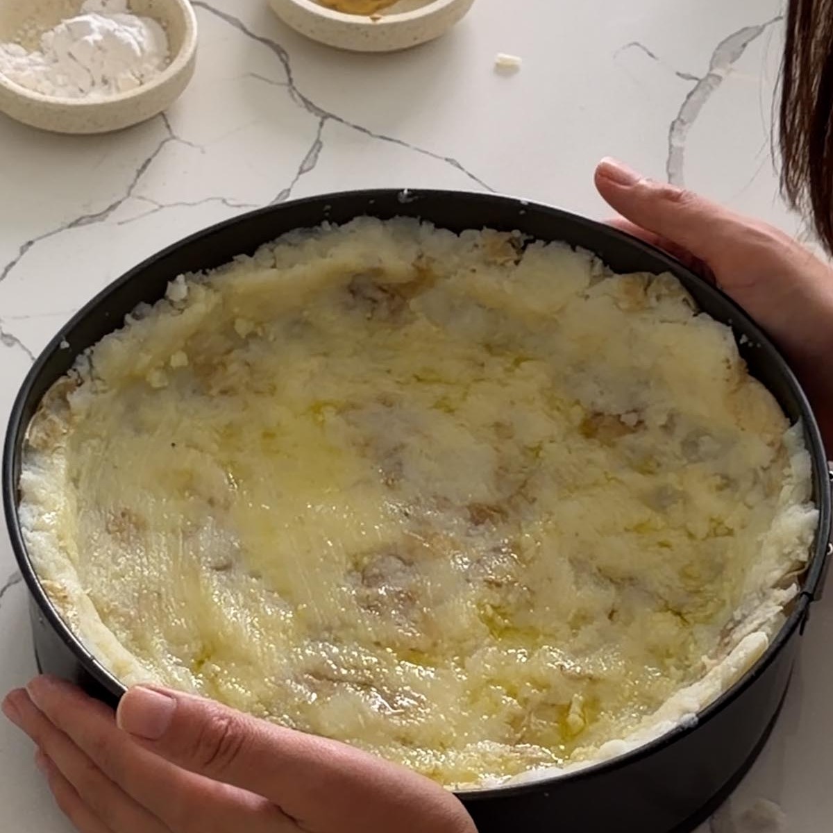 an oiled potato crust pressed into a springform pan, ready to bake.
