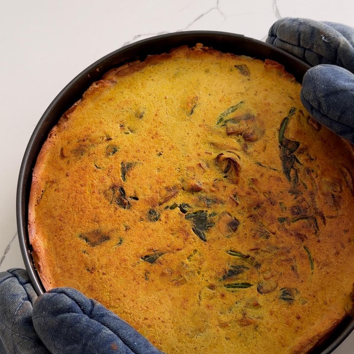 the baked potato crust quiche coming out of the oven in its springform pan.