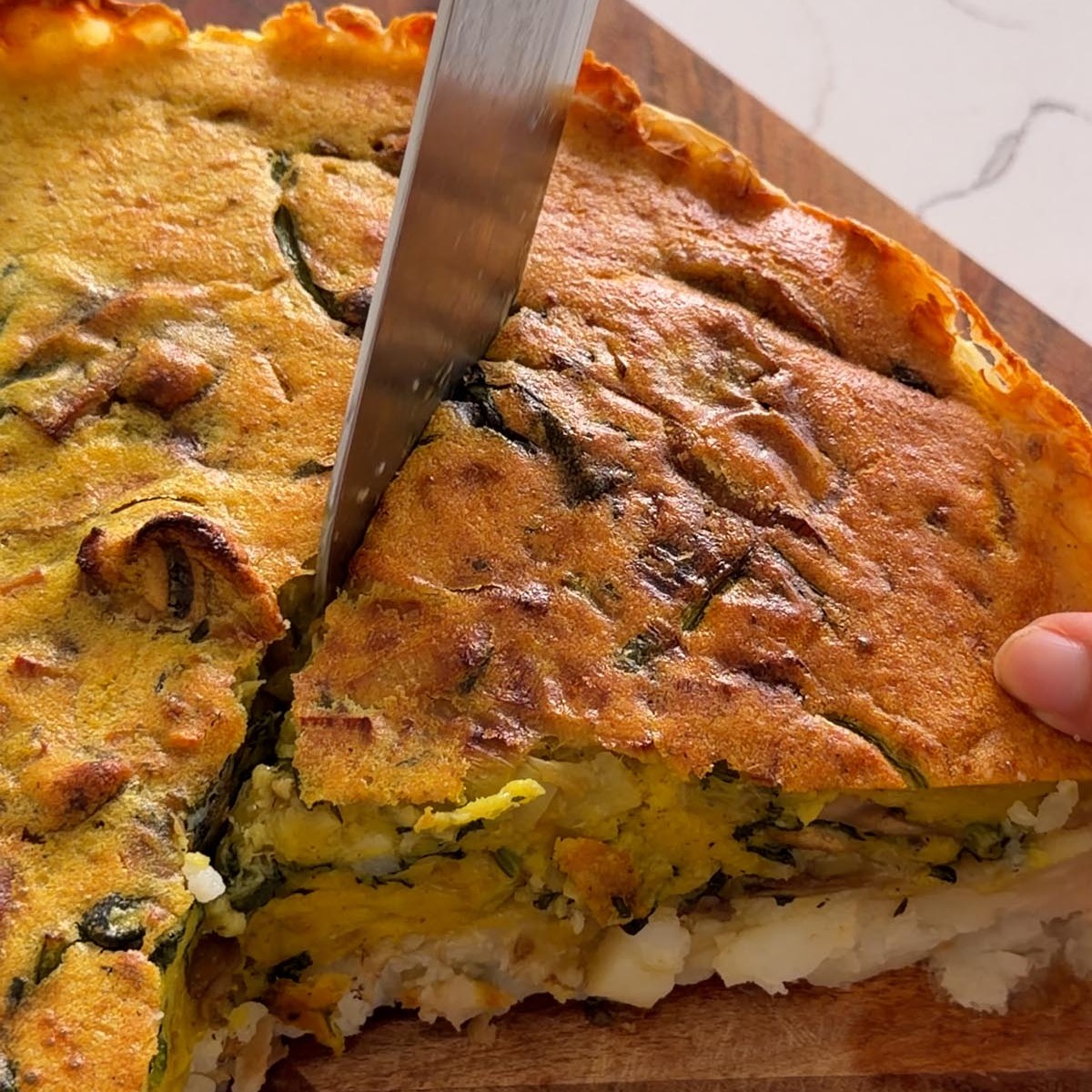 lifting the first slice of potato crust quiche, showing the potato base underneath.